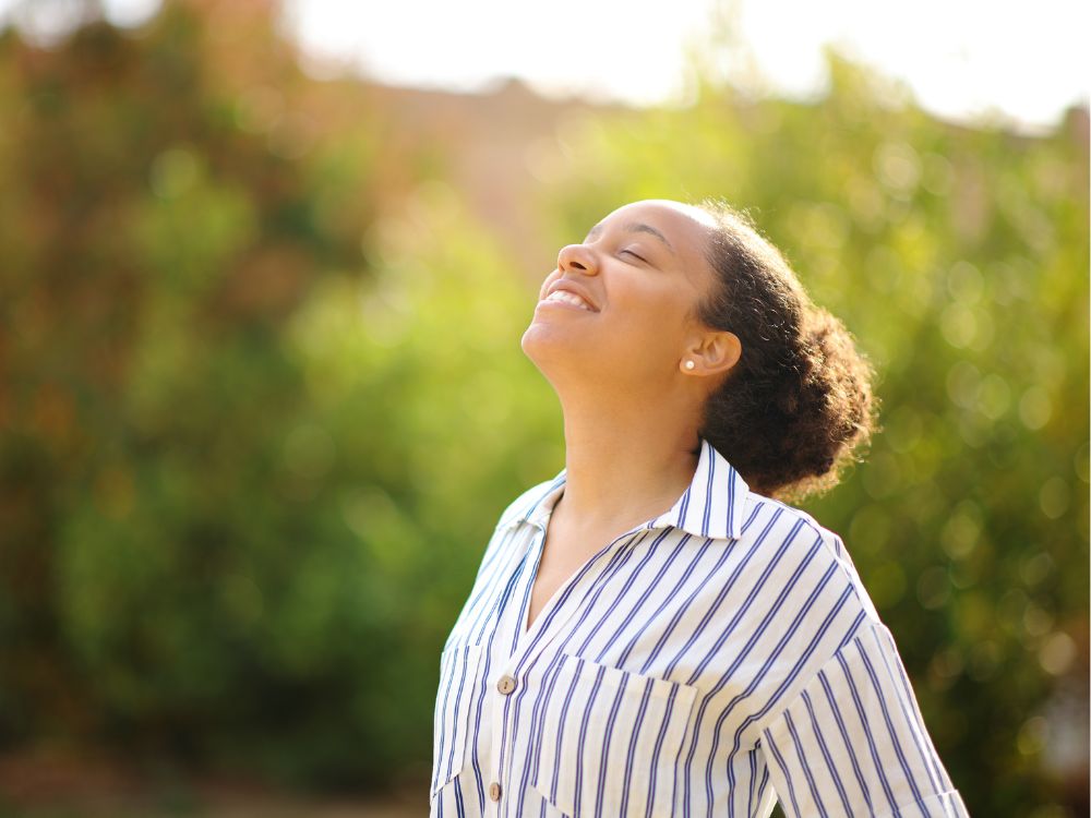 Uma mulher respirando ar puro e em estado de meditação.