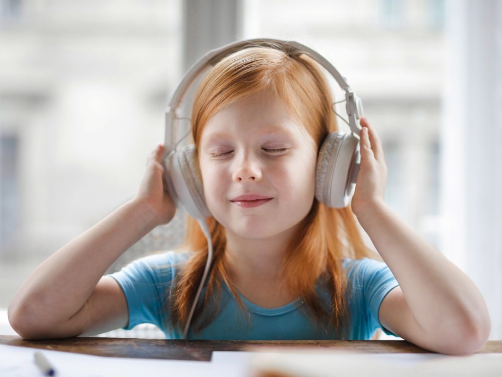 Menina ruiva com fones. Uma menina ruiva acalmando a sua mente. Ela está de olhos fechados e com fone de ouvido.